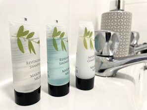 Three bottles of shower products with green leaf designs on a bathroom counter. - Vibrant 6 bed Stylish Home in Heart of Southsea (Portsmouth)