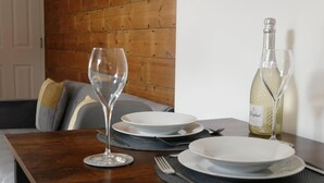 A dining table set with white plates, a wine glass, and a bottle of white wine. - Vibrant 6 bed Stylish Home in Heart of Southsea (Portsmouth)