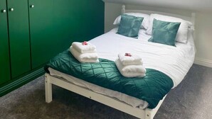 A bedroom with a skylight, a bed with green bedding, and a green wardrobe. - Vibrant 6 bed Stylish Home in Heart of Southsea (Portsmouth)