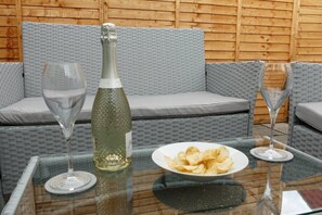 A glass table with a bottle, two glasses, and a plate of chips. - Vibrant 6 bed Stylish Home in Heart of Southsea (Portsmouth)