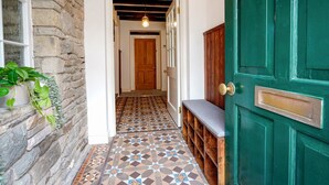 A hallway with a patterned tile floor, a wooden bench, and a green door. - The Old Bulls Head (High Peak)