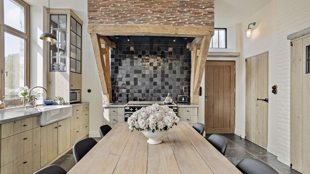 A modern kitchen with a large island, wooden cabinets, and a decorative tile backsplash.