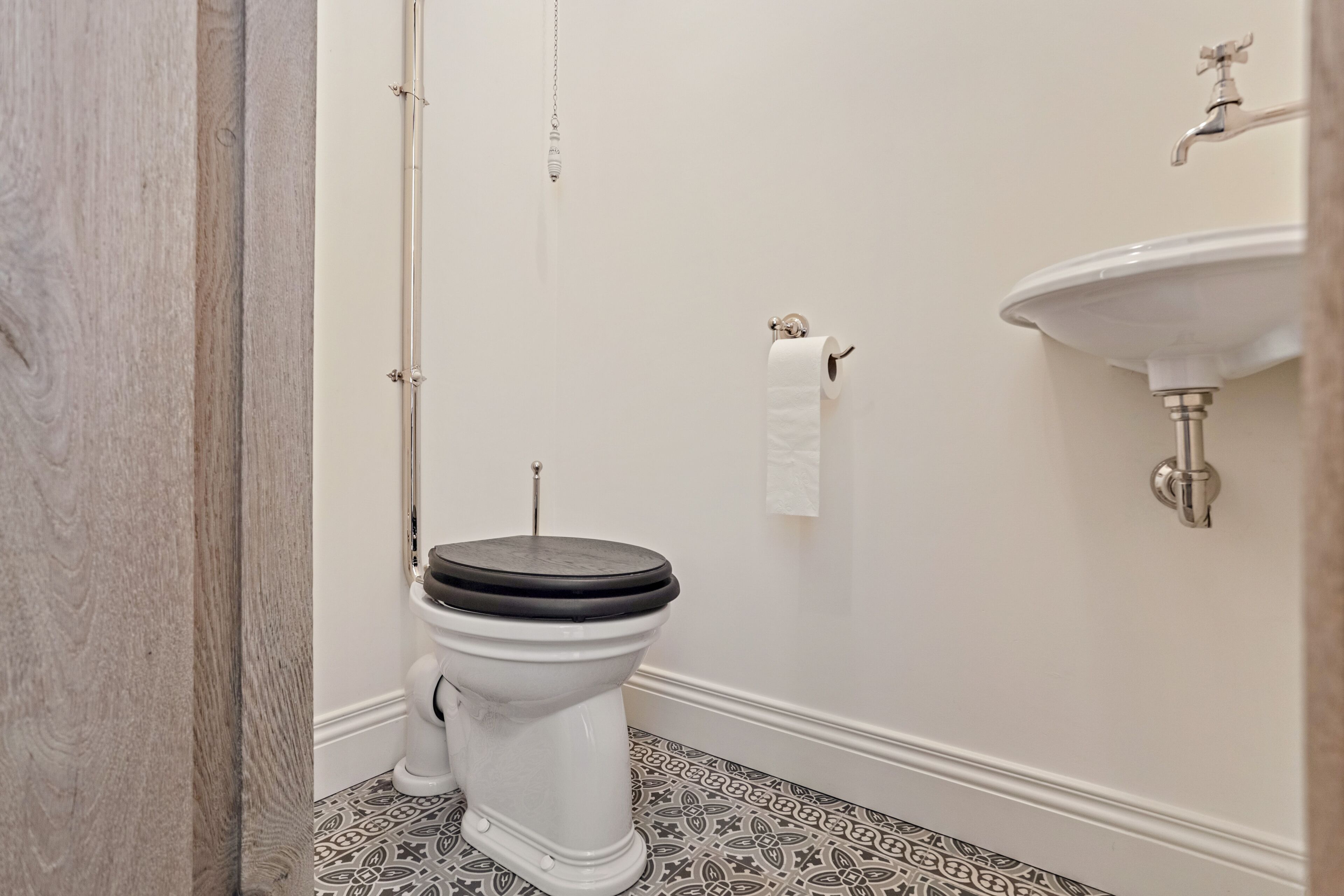 A bathroom with a toilet, a sink, and patterned floor tiles.