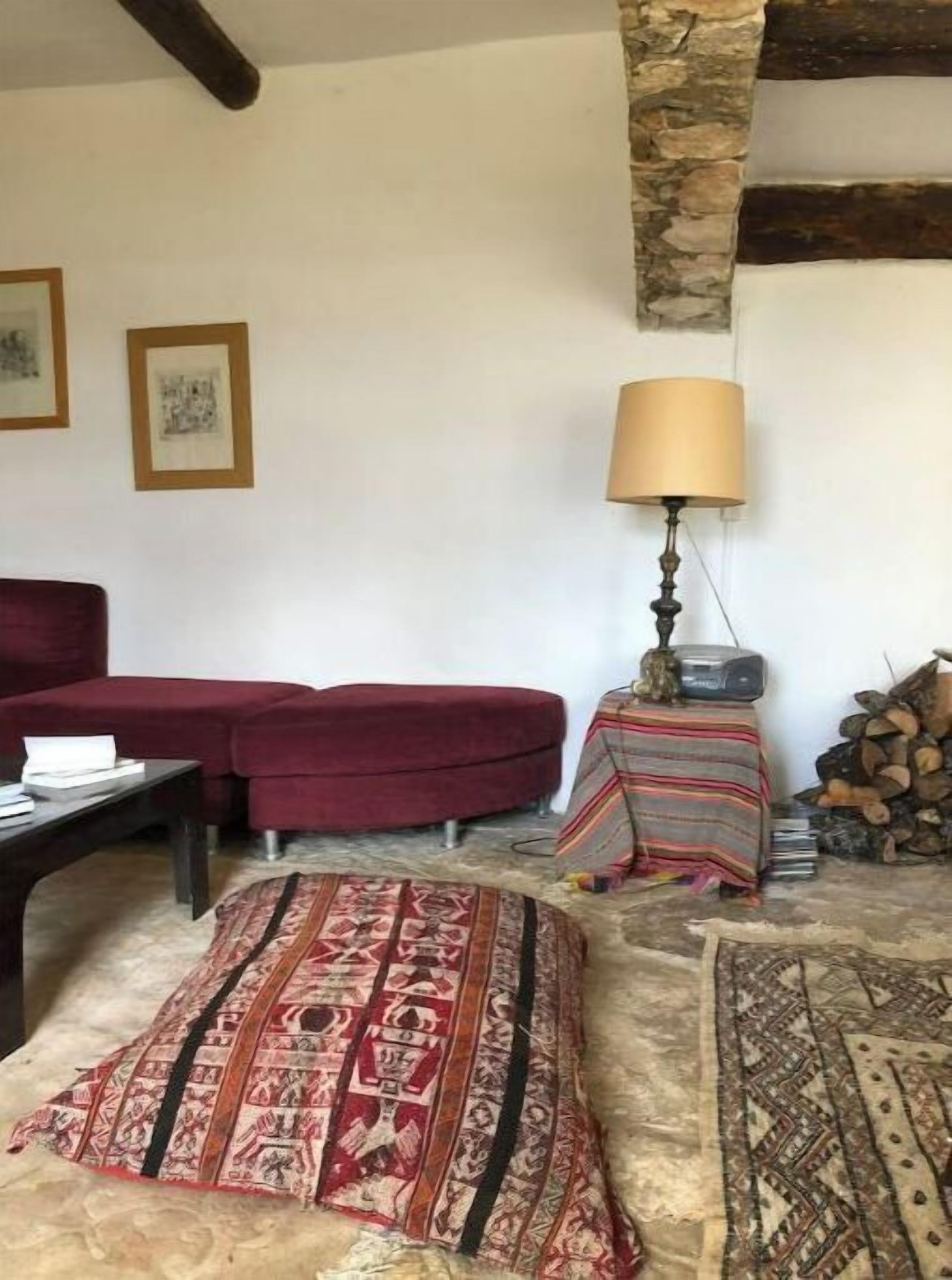 En hyggelig stue med en rød sofa, et tæppe med et mønster, en lampe og et lille bord med en radio.