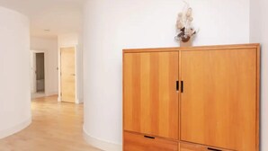 A hallway with a wooden wardrobe, a light fixture, and a door leading to another room.