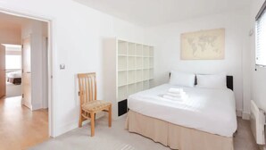 A bedroom with a bed, a chair, a wardrobe, and a world map on the wall.