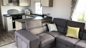 Eine moderne Küche mit Einbauherd, einem Essbereich und einem grauen Ecksofa mit gelbem Kissen.