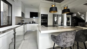 Une cuisine moderne dotée d’un îlot central, d’appareils électroménagers en acier inoxydable et d’une grande fenêtre.