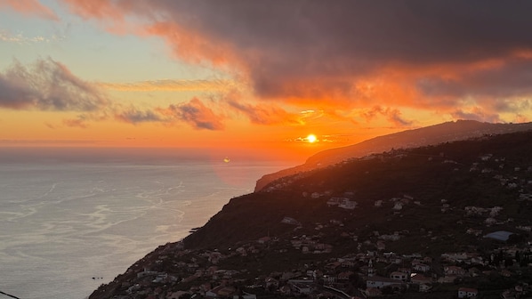 Une ville côtière au coucher du soleil, avec vue sur la mer et une montagne.