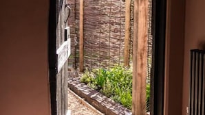 An open doorway leading to a garden area with a brick wall and wooden posts.