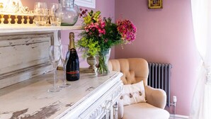 A room with a marble table, a bottle of champagne, and a vase of flowers.