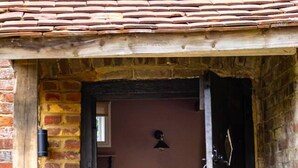 A rustic brick building with a wooden door leading to a kitchen area.