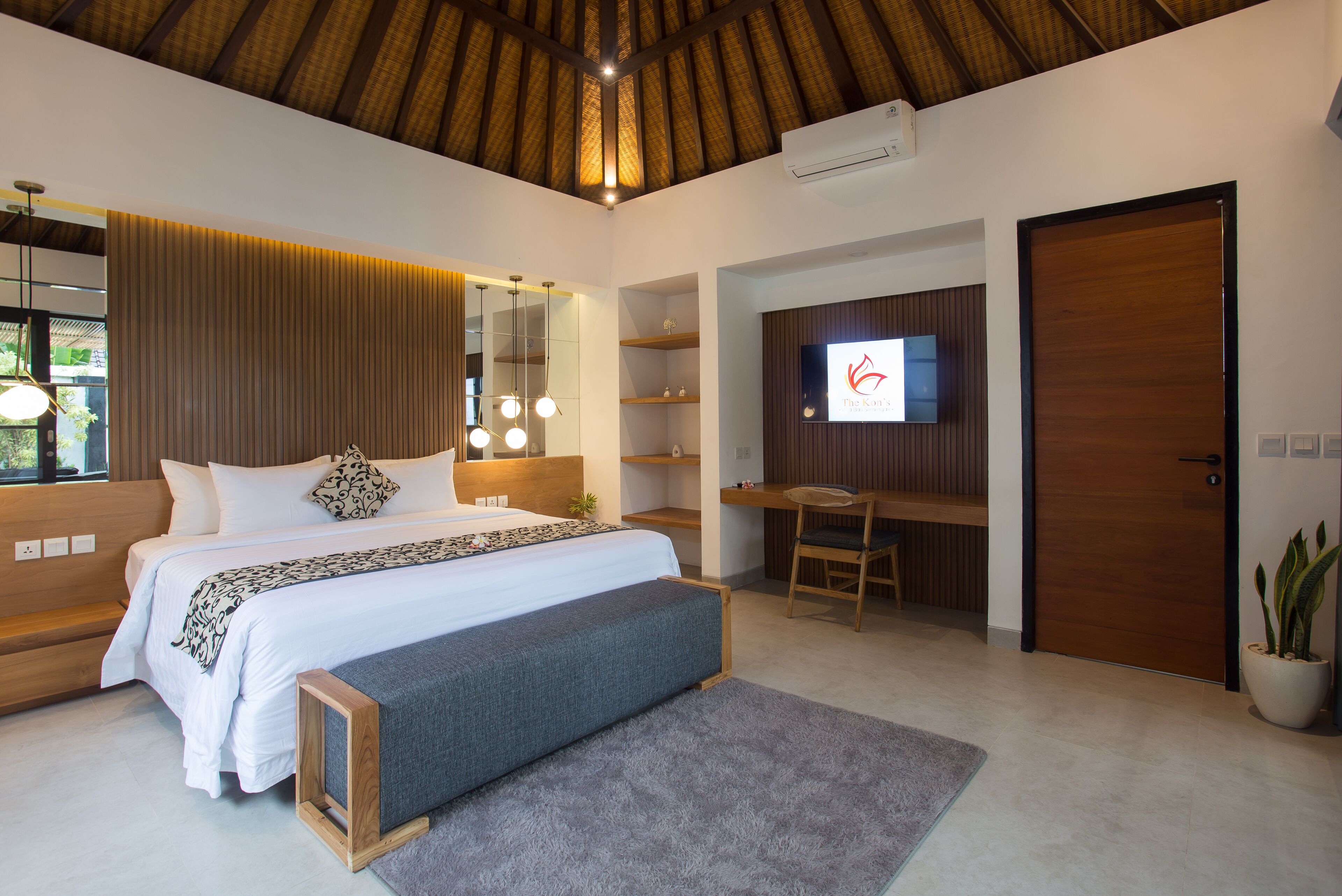 A modern bedroom with a large bed, a desk, and a TV.