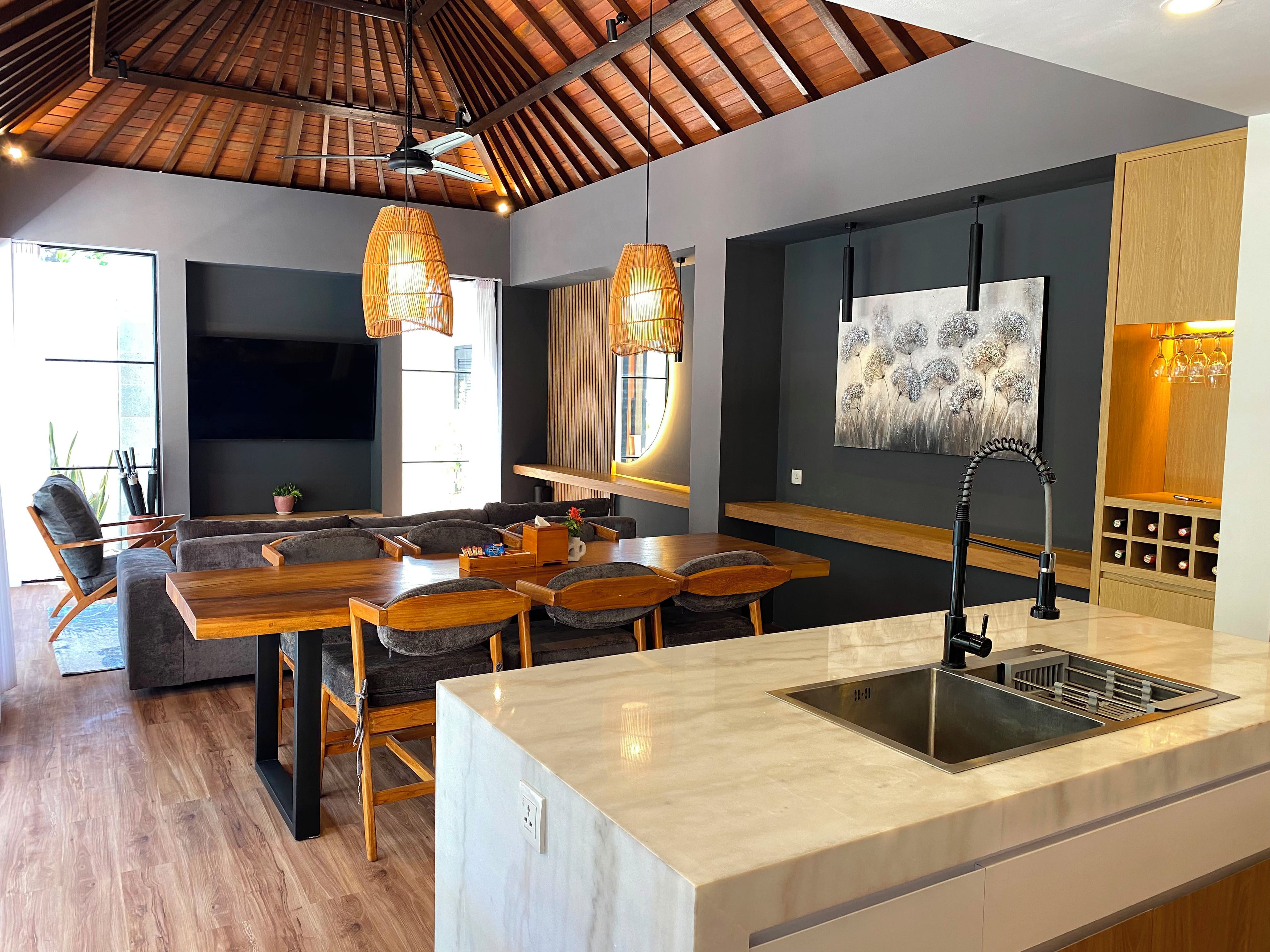 Una cocina moderna con una isla grande, piso de madera e iluminación colgante.