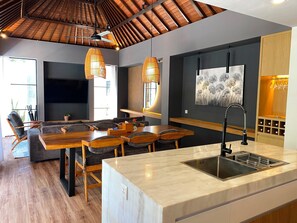 A modern kitchen with a large island, wooden flooring, and pendant lighting. - The Kons Villa Bali Seminyak (Seminyak)