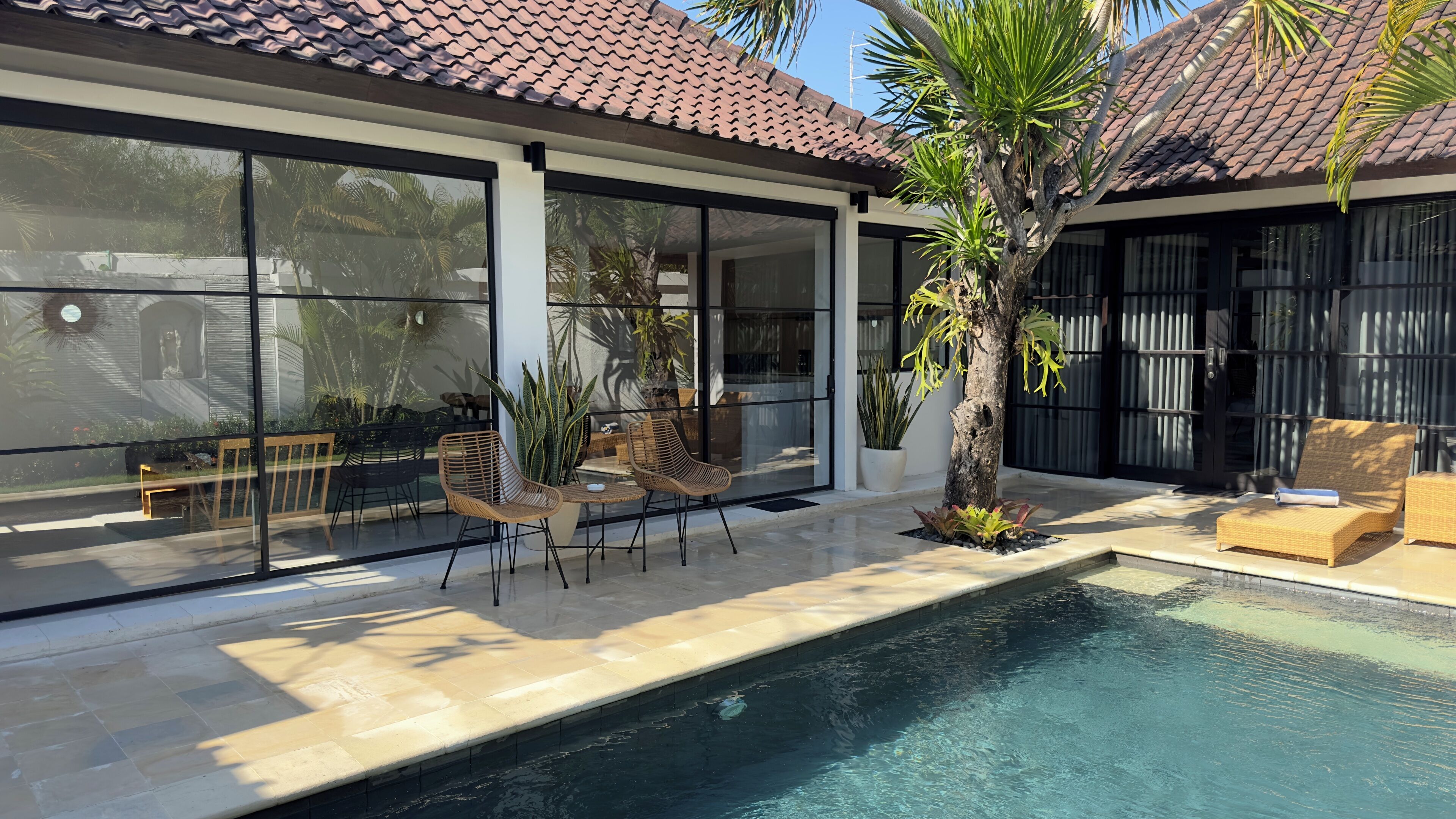 A modern outdoor pool area with a tiled roof, large windows, and outdoor seating.