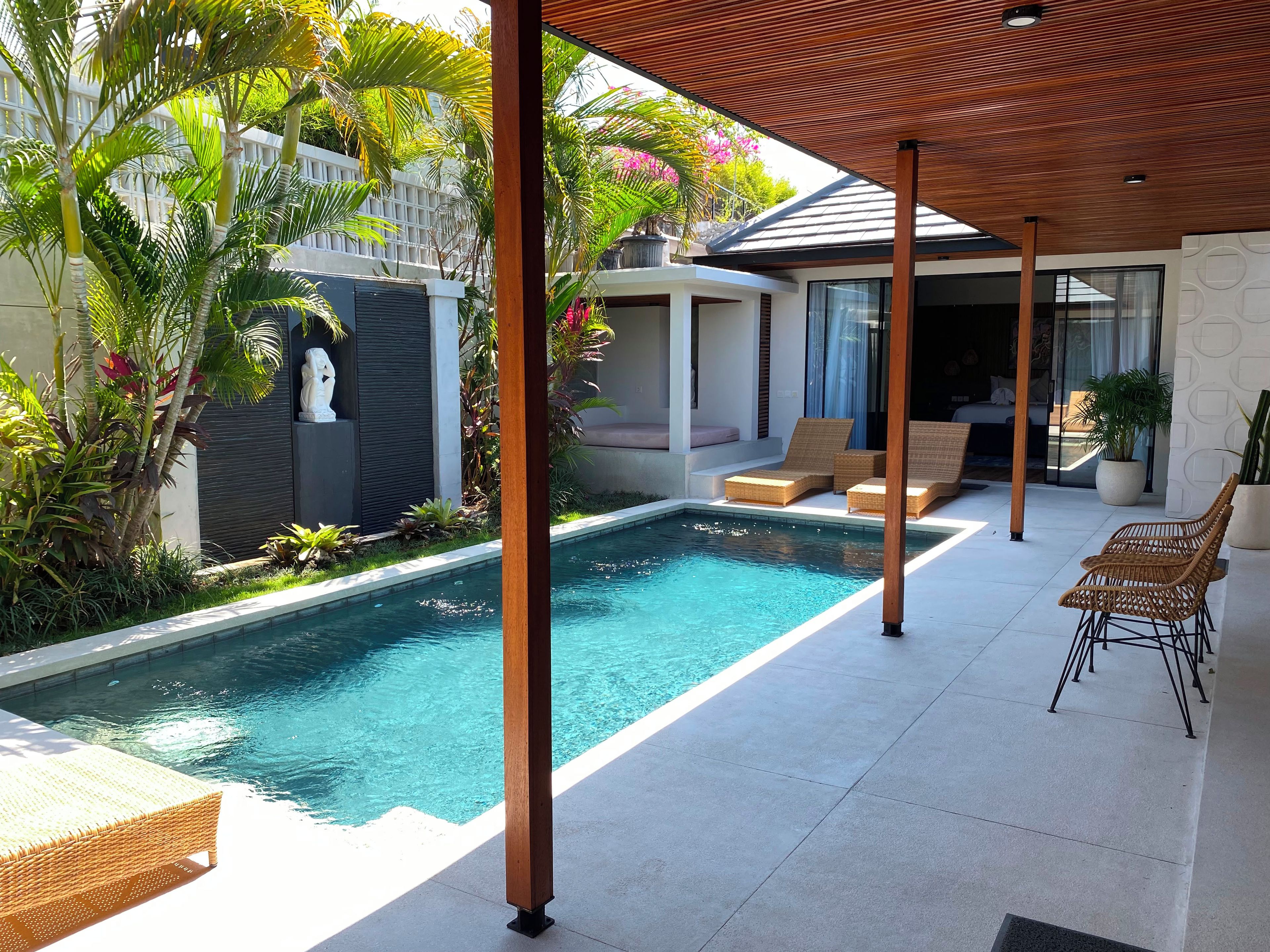 A modern outdoor pool area with lounge chairs and a covered seating area.