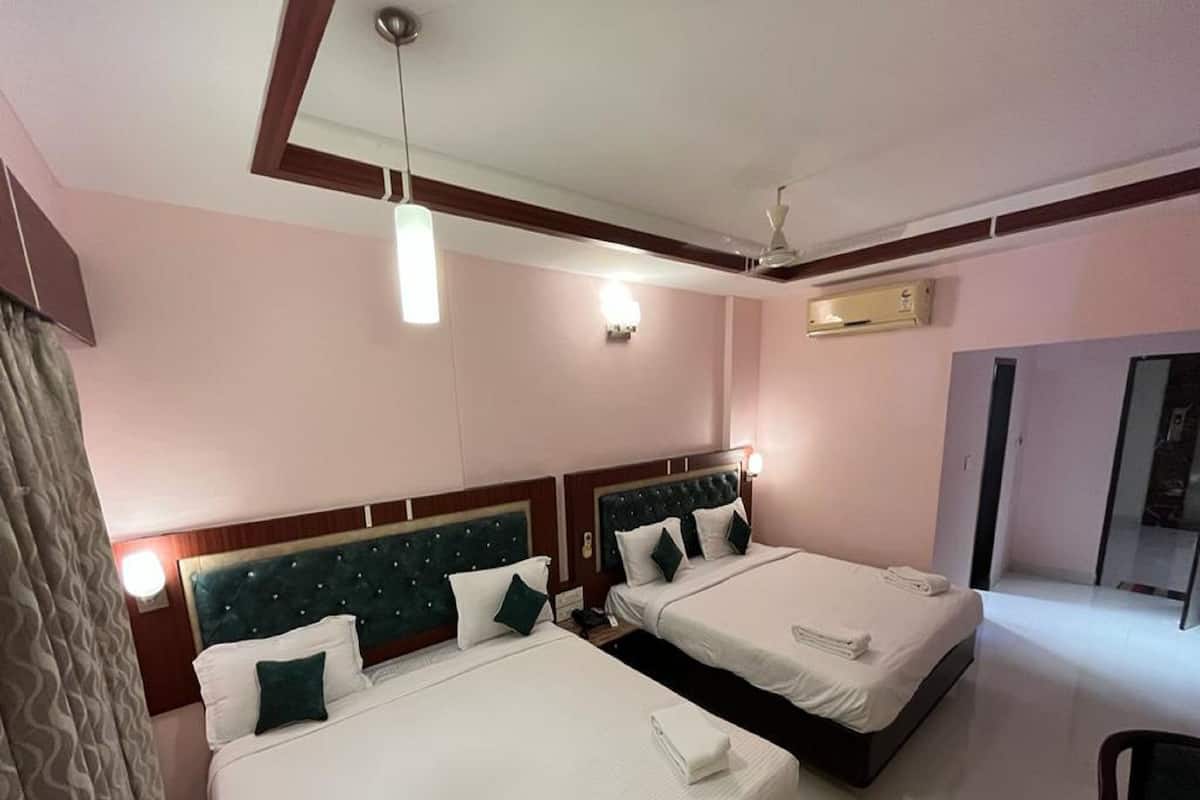 A hotel room with two beds, each with a headboard and pillows, a bedside table, a mirror, and a ceiling fan.
