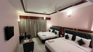 A hotel room with two beds, a desk, a chair, and a TV. - Daffodil Inn (Kilvelur)