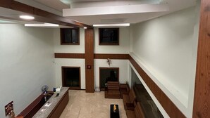 A spacious hotel lobby with a high ceiling, multiple windows, and a central seating area. - Daffodil Inn (Kilvelur)