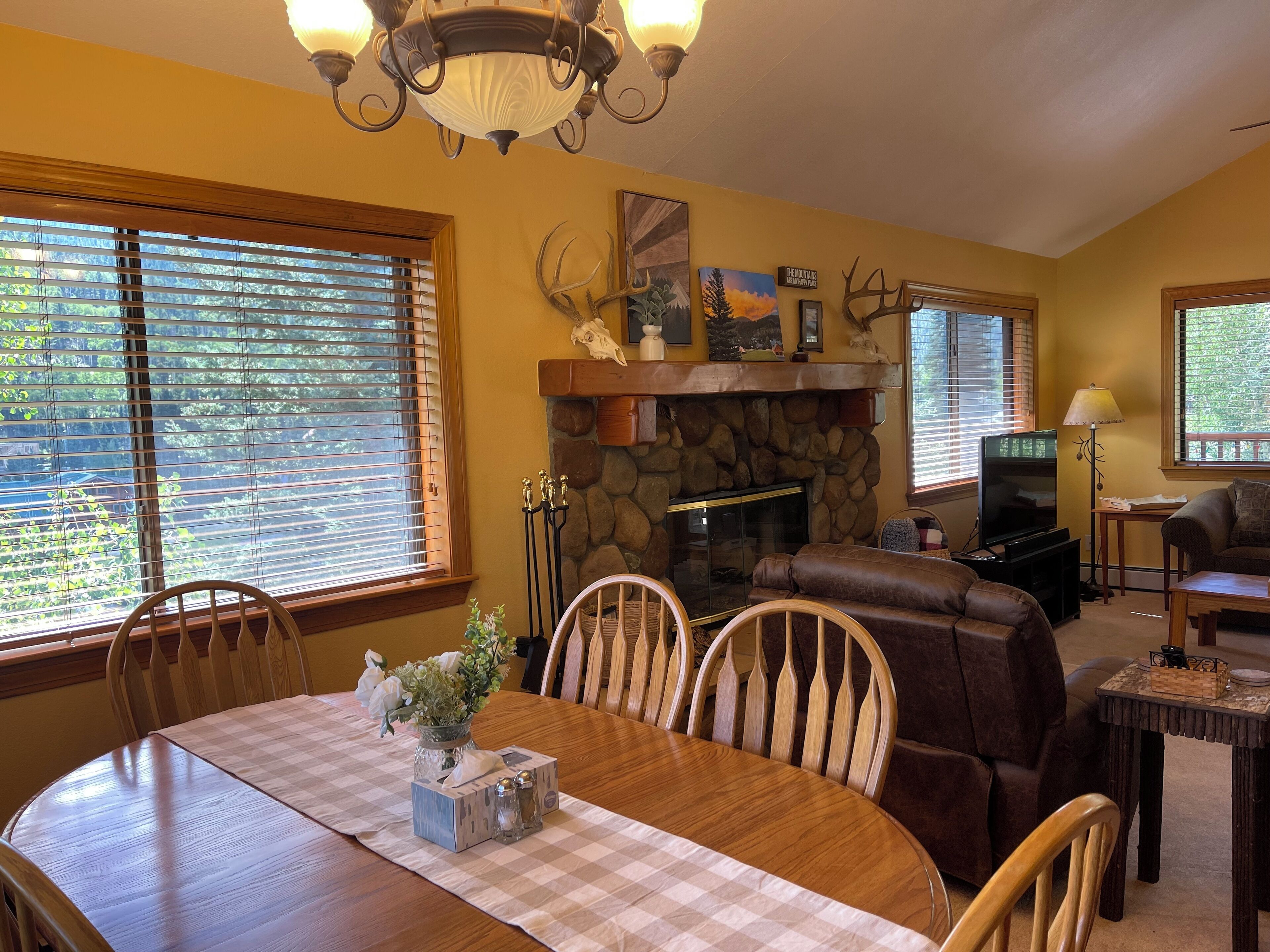 A dining area with a wooden table and chairs, a fireplace, and a stone wall.