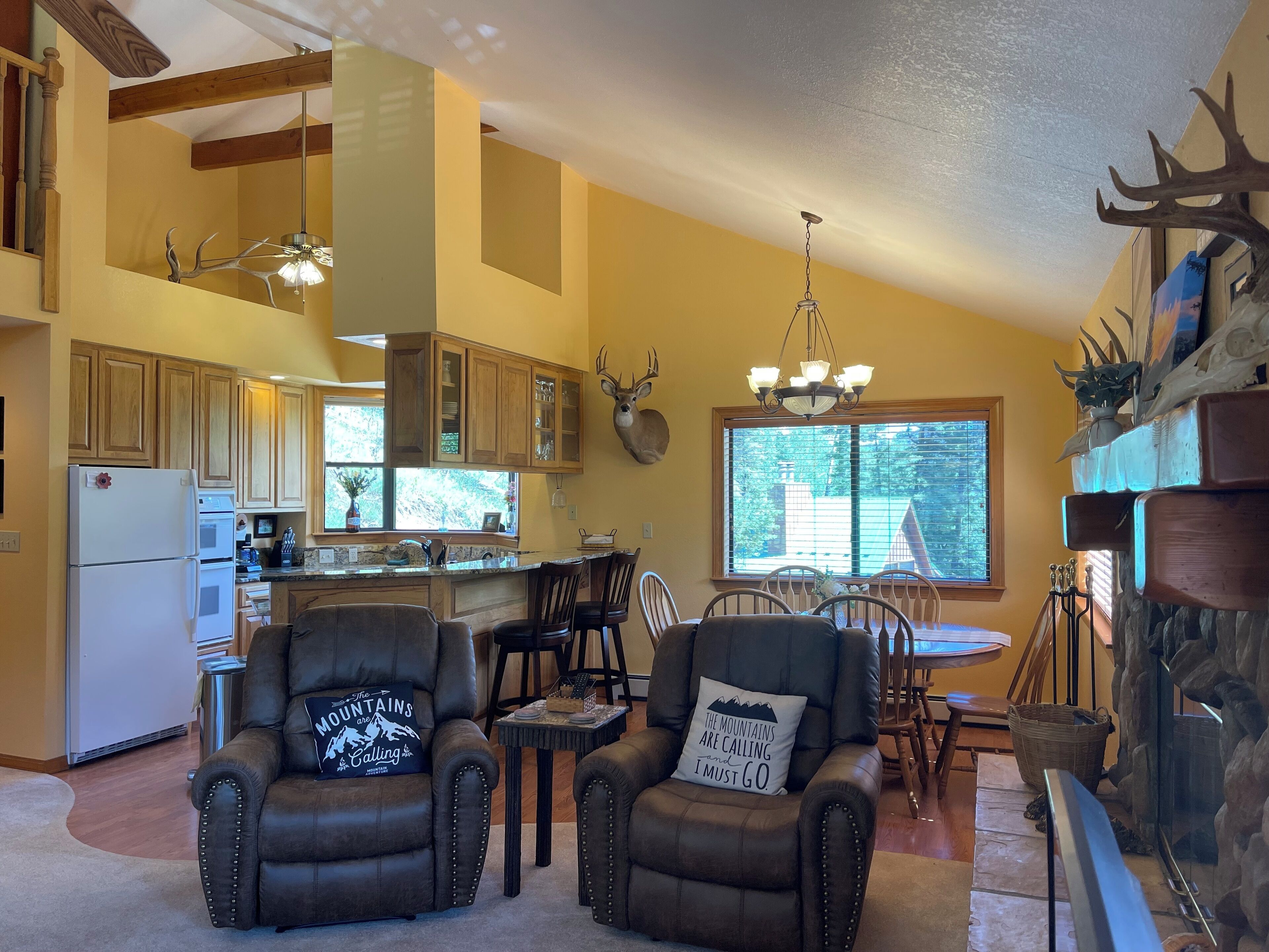 A spacious living area with a fireplace, leather armchairs, and a dining table.
