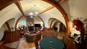 Una sala de estar estilo loft acogedora, con chimenea, muebles de madera y techo abovedado.