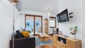 A modern living room with a sofa, coffee table, TV, and wooden cabinet.