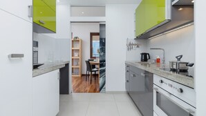 A modern kitchen with white cabinets, a granite countertop, and a built-in oven.
