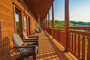 A wooden deck with Adirondack chairs and a railing overlooking a forested area. - GraceView Lodge: Indoor Pool, Mtn Views, Large Outdoor Patio, Fire Pit, Hot Tub, Theater and more... (Sevierville)