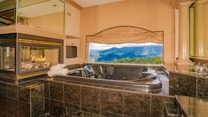 A modern bathroom with a large window, a built-in hot tub, and a mirror above the sink.