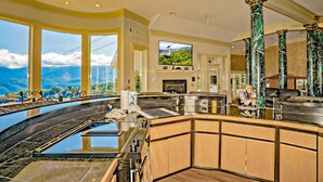 A luxurious kitchen with a large island, a fireplace, and a view of the mountains.