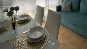 Een eethoek met een tafel voor vier personen, een bank en een raam met gordijnen.