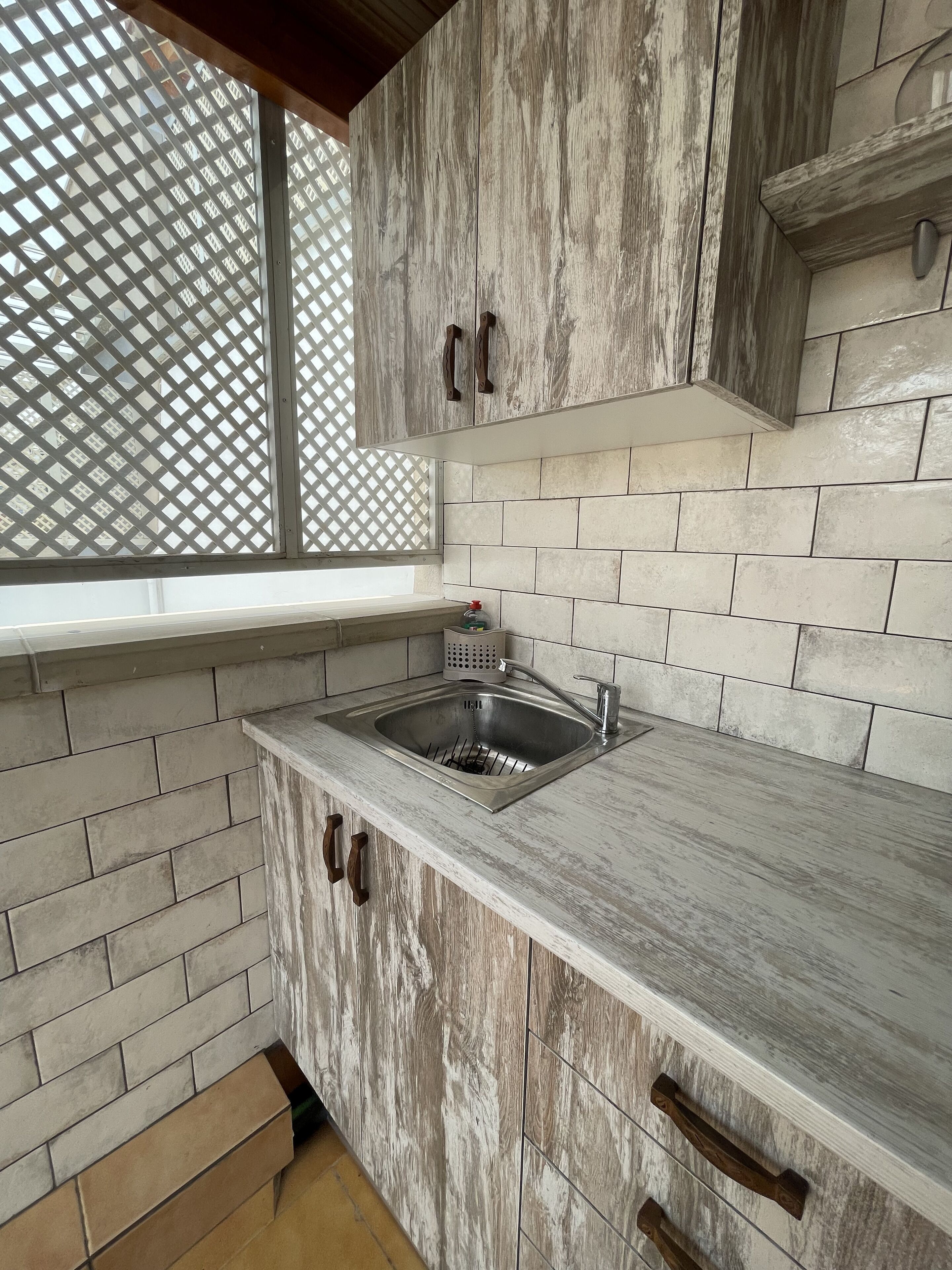 A kitchen with a built-in sink, wooden cabinets, and a window with a lattice design.