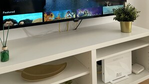 Een flatscreen televisie op een witte tv-meubel, waarop het Disney logo en een afbeelding van het kasteel staan.