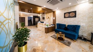 A modern lobby with a reception desk, a blue sofa, and a potted plant. - Bangalore Times by Alaya Stays (Bengaluru)