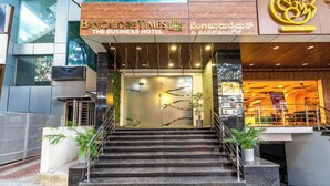 A hotel entrance with a staircase, a glass door, and a sign for 'BANGALORE TIMES THE BUSINESS HOTEL'. - Bangalore Times by Alaya Stays (Bengaluru)