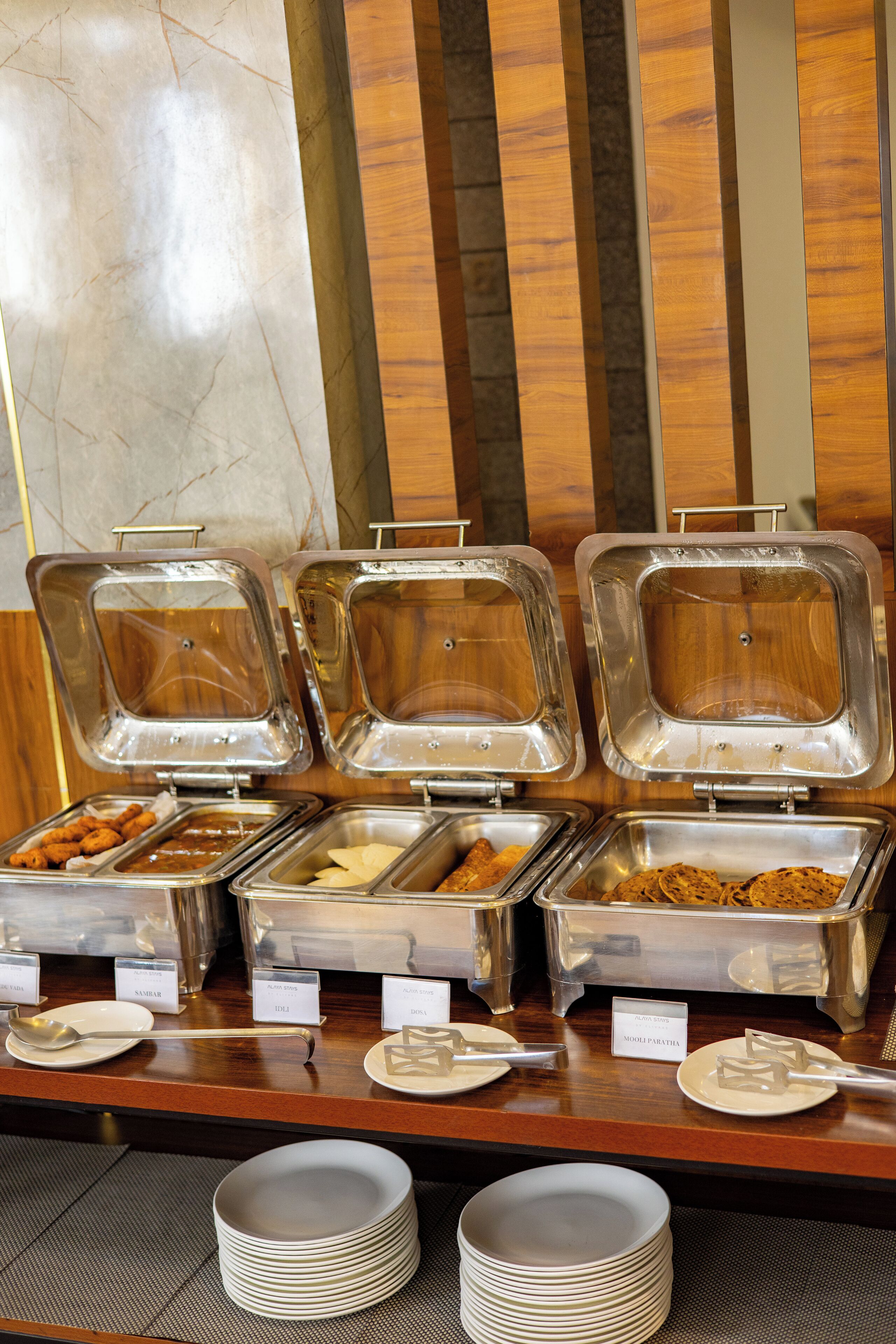 A buffet setup with labeled containers of food, including a variety of dishes and utensils.