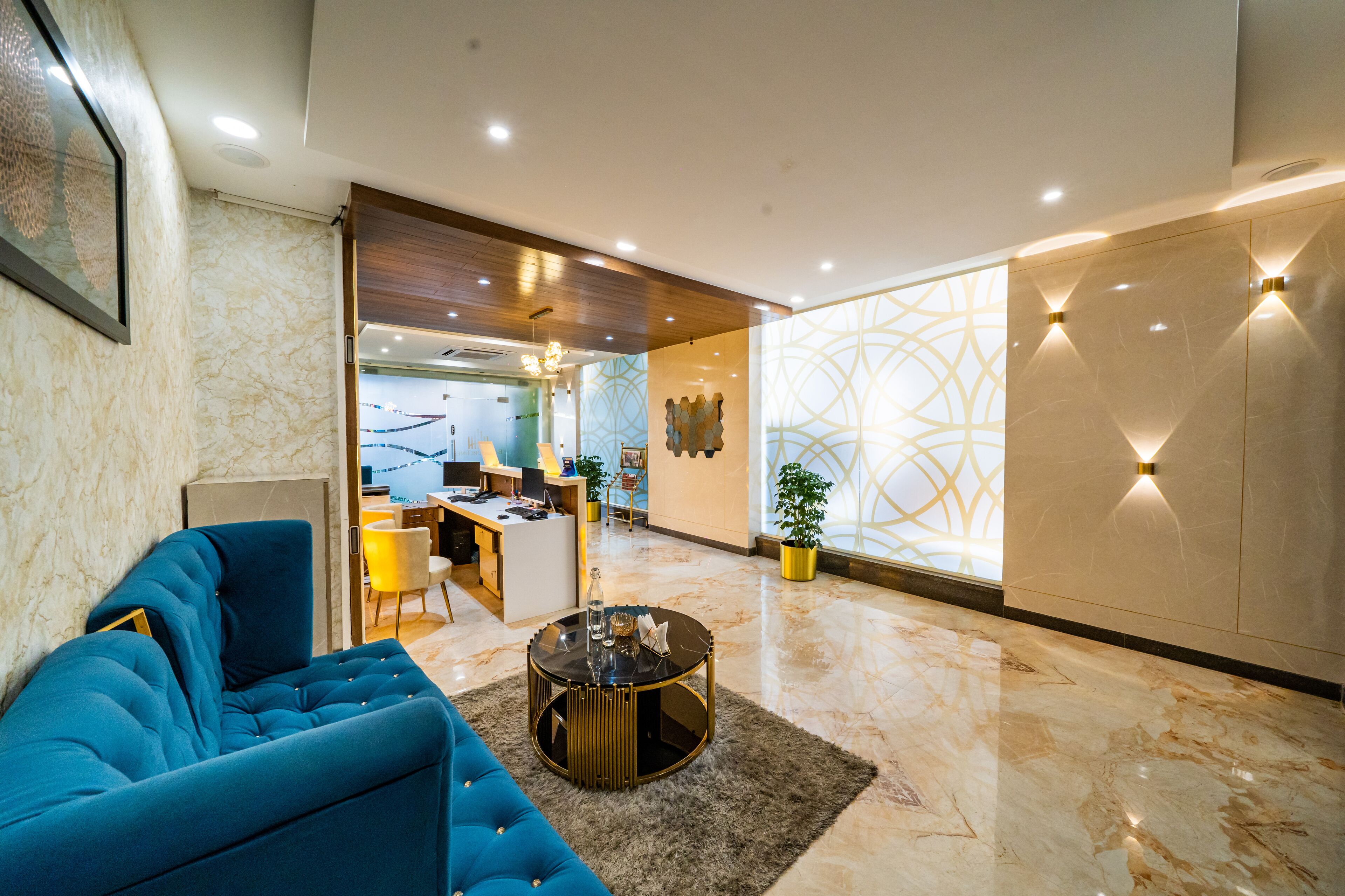 A modern lobby with a blue sofa, a round coffee table, and a desk area.