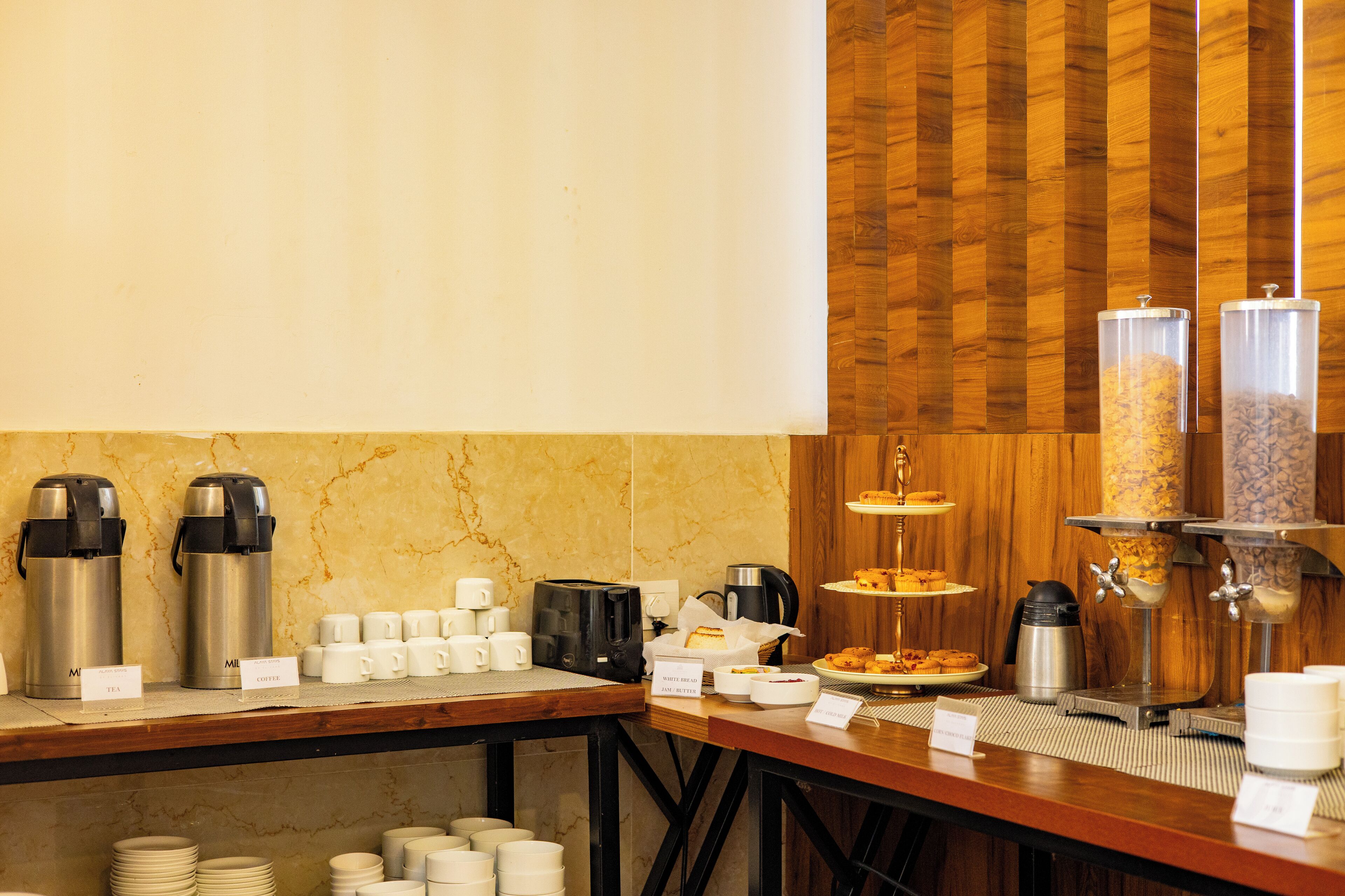 A breakfast buffet setup with coffee makers, cups, and a variety of food items.