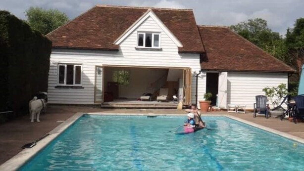 Una casa con piscina, un perro y una persona en flotador.