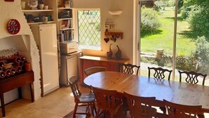 Una cocina acogedora con una mesa y sillas de madera, un refrigerador y una ventana con vistas a un jardín.