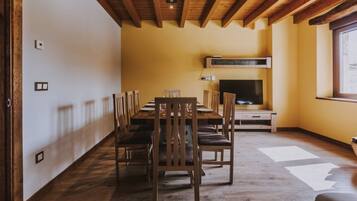 A dining area with a wooden table and chairs, a television, and a fireplace.