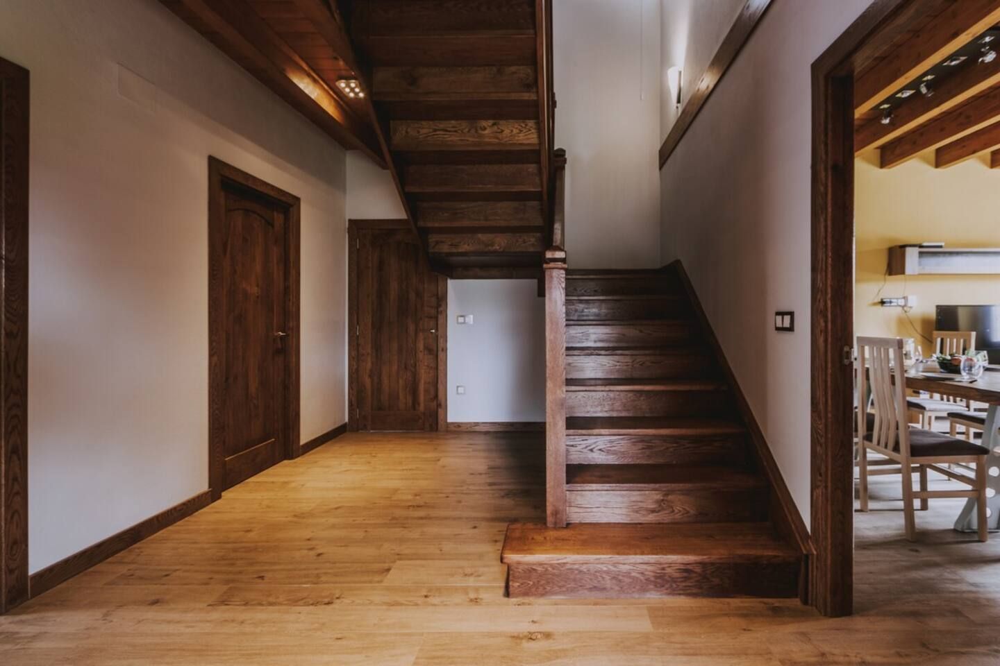 Una escalera de madera que lleva a un comedor con sillas y una mesa.