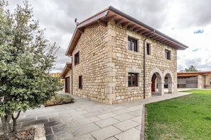 A stone building with a flat roof, a paved entrance, and a grassy area in front. - 4 bedroom accommodation in Norte (Villadiego)