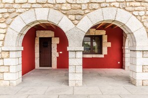 A stone archway leading to a red door with a window above it.
