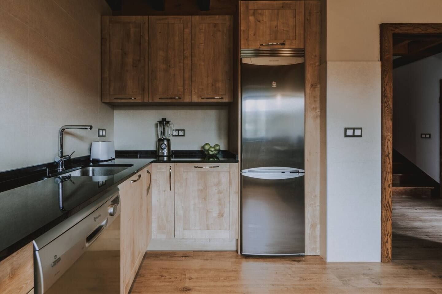 Una cocina moderna con gabinetes de madera, electrodomésticos de acero inoxidable y lavavajillas integrado.