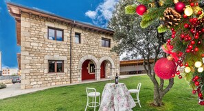A stone building with a red door, a table with chairs, and Christmas decorations. - 4 bedroom accommodation in Norte (Villadiego)
