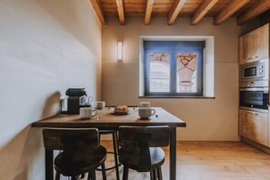 A small kitchen with a window, wooden cabinets, and a table with chairs.