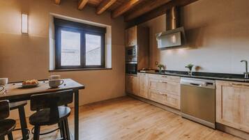 A kitchen with wooden cabinets, a window, and a dining area with stools.